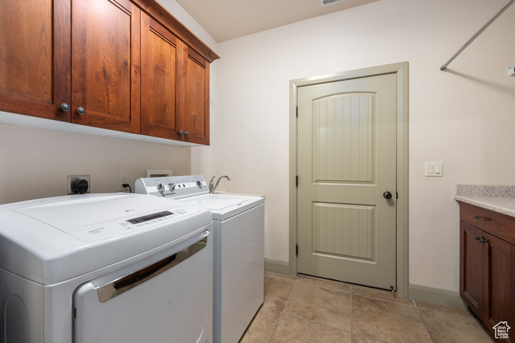 Clothes washing area with baseboards, cabinet space, and independent washer and dryer