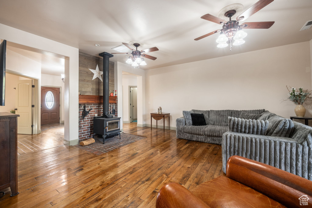 Living area featuring baseboards, ceiling fan, a wood stove, and hardwood / wood-style floors