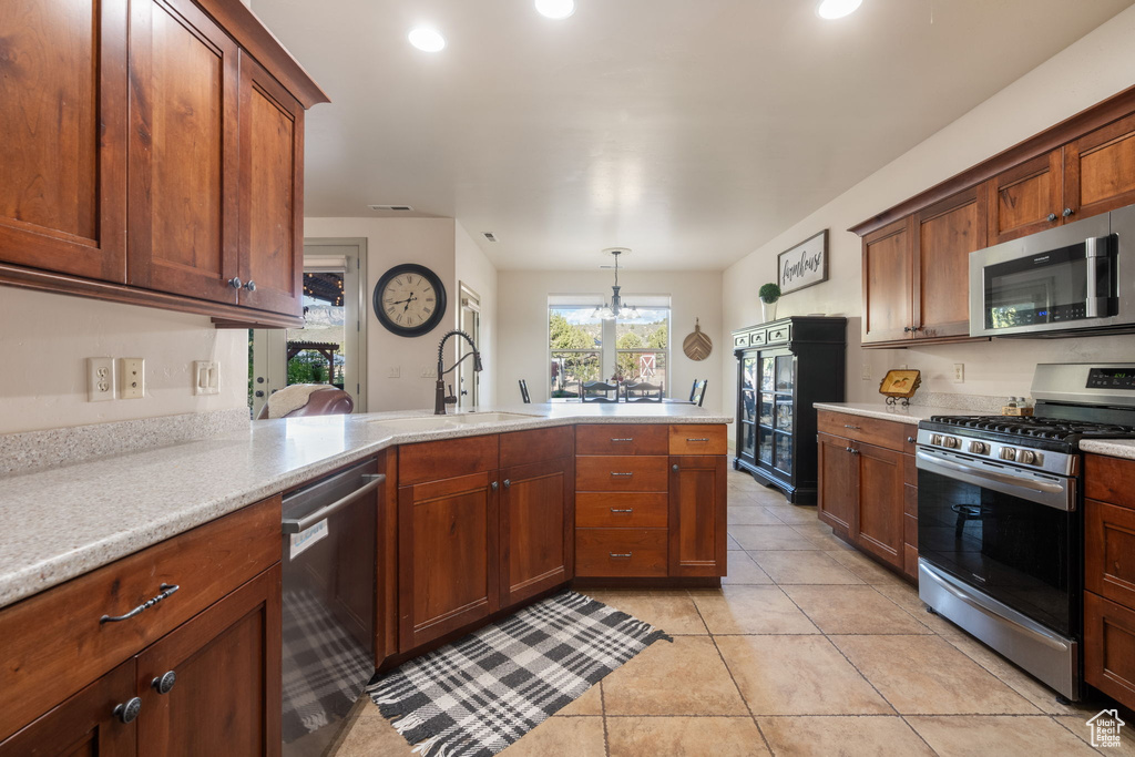 Kitchen featuring appliances with stainless steel finishes, a sink, light countertops, a peninsula, and light tile patterned flooring