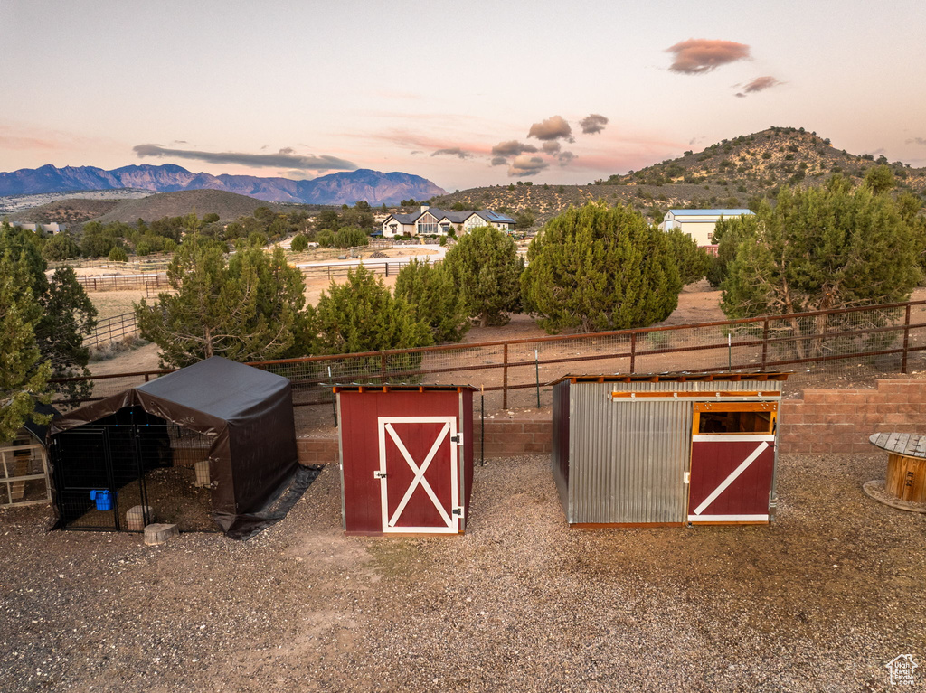 View of outbuilding featuring an outdoor structure, a mountain view, and fence