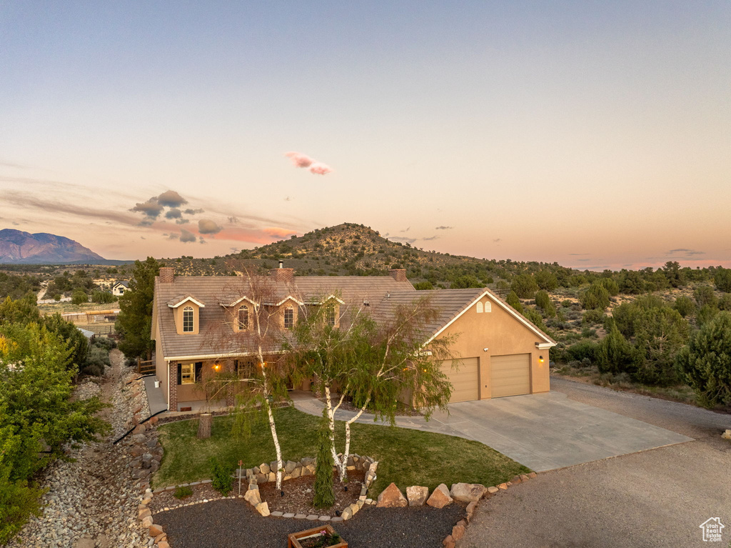 View of front of property with a garage, a mountain view, a chimney, and concrete driveway
