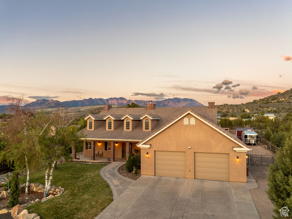 View of front of house with a porch, a lawn, fence, a mountain view, and concrete driveway
