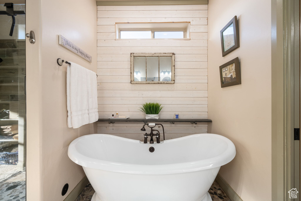 Bathroom with wooden walls, baseboards, and a soaking tub