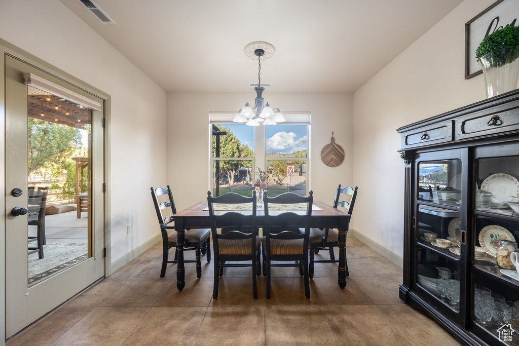 Dining space with visible vents, baseboards, a chandelier, and a healthy amount of sunlight