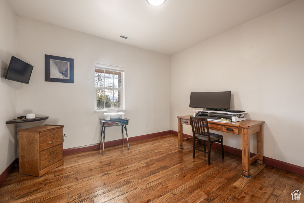 Office space featuring baseboards, visible vents, and hardwood / wood-style floors