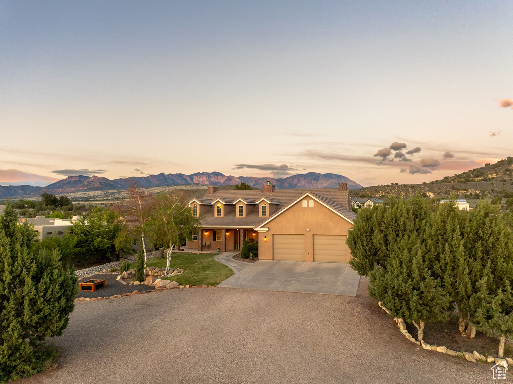 View of front of property featuring covered porch, driveway, a chimney, a mountain view, and an attached garage