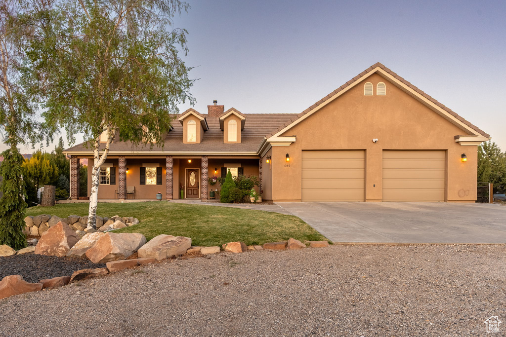 View of front of property with a front lawn, a garage, a chimney, concrete driveway, and covered porch