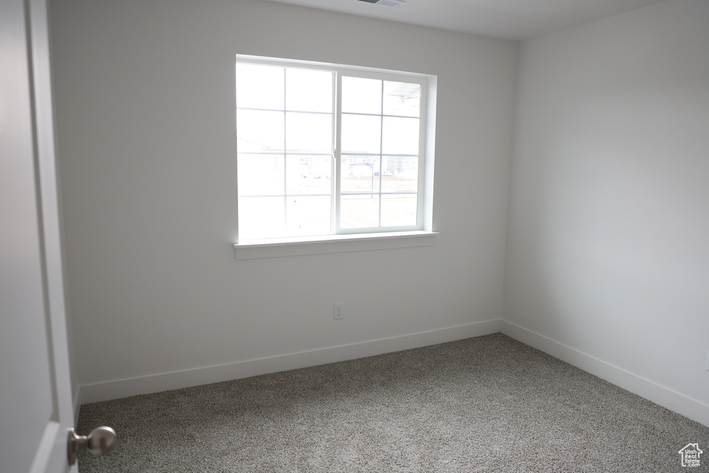 Empty room with carpet floors, baseboards, and visible vents