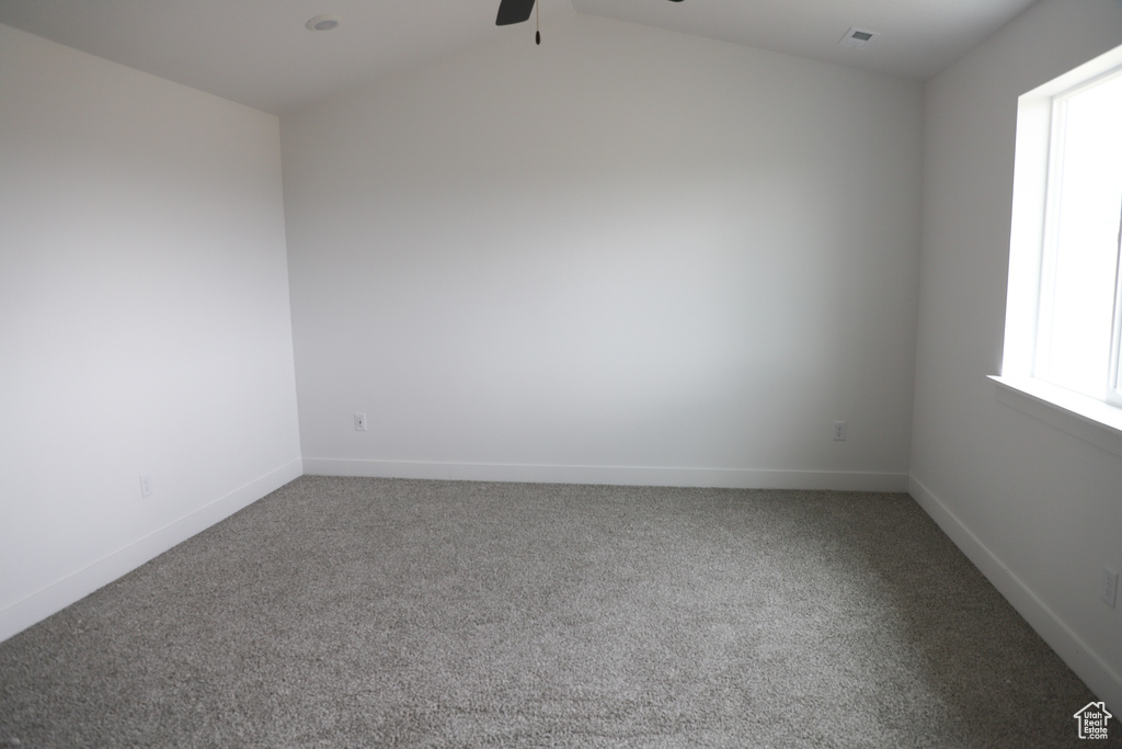 Unfurnished room featuring carpet floors, baseboards, a ceiling fan, and lofted ceiling