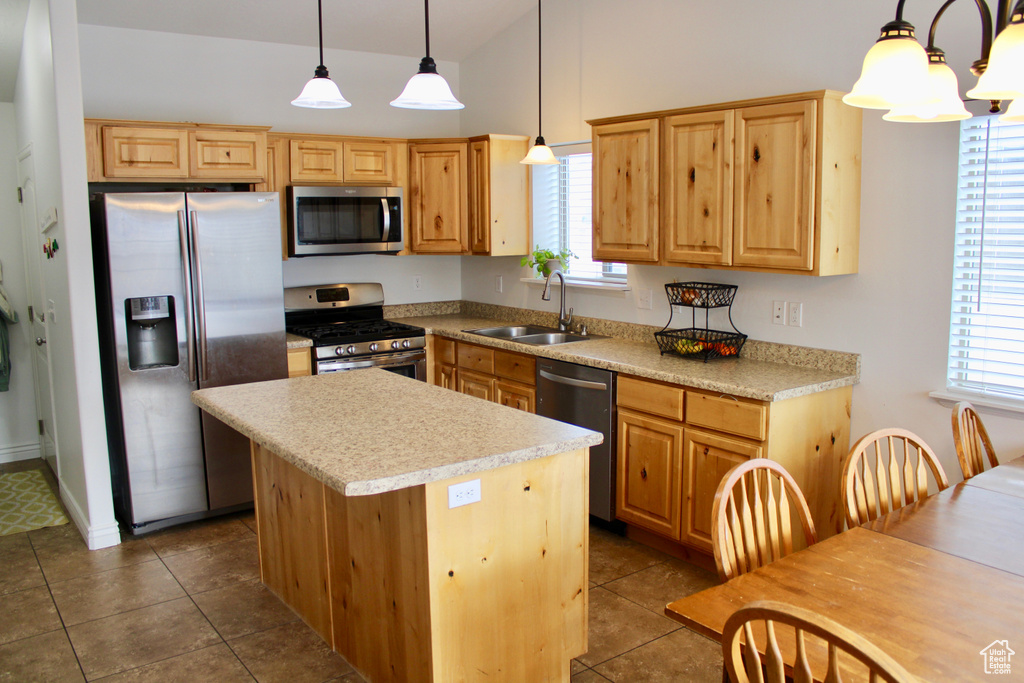 Kitchen featuring a kitchen island, vaulted ceiling, a sink, light countertops, and stainless steel appliances