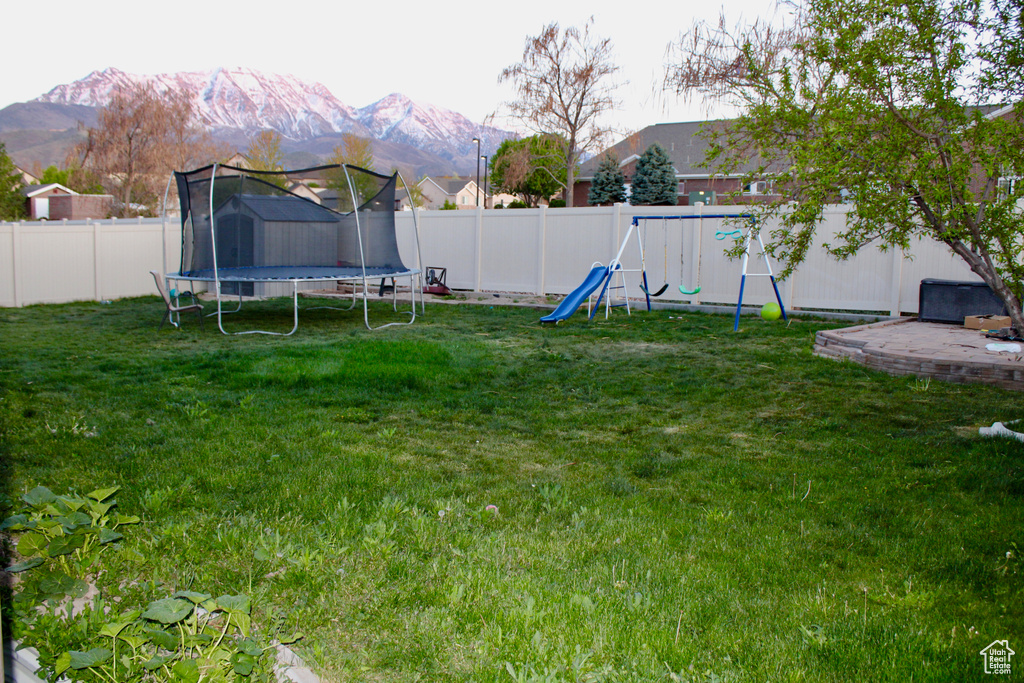 View of yard with a fenced backyard, a trampoline, a playground, and a mountain view