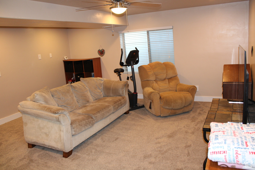 Carpeted living area featuring a ceiling fan and baseboards