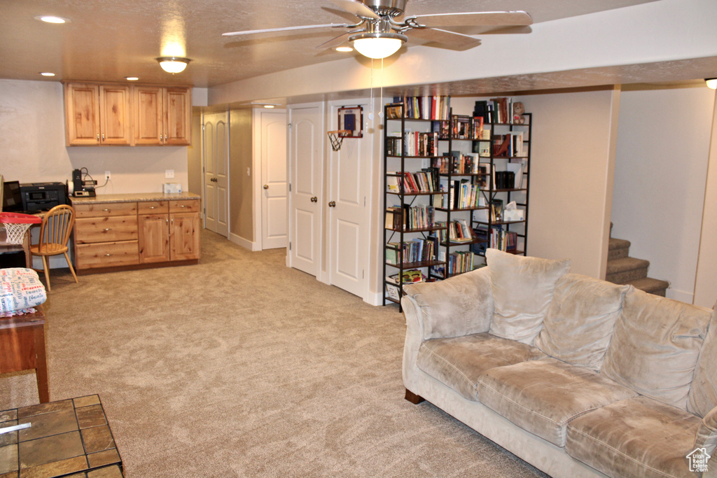 Living area with recessed lighting, ceiling fan, light carpet, and stairway