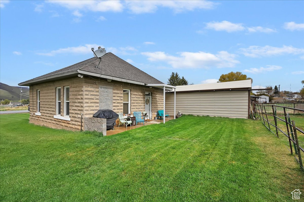 Back of house with a patio area, fence, a yard, and roof with shingles