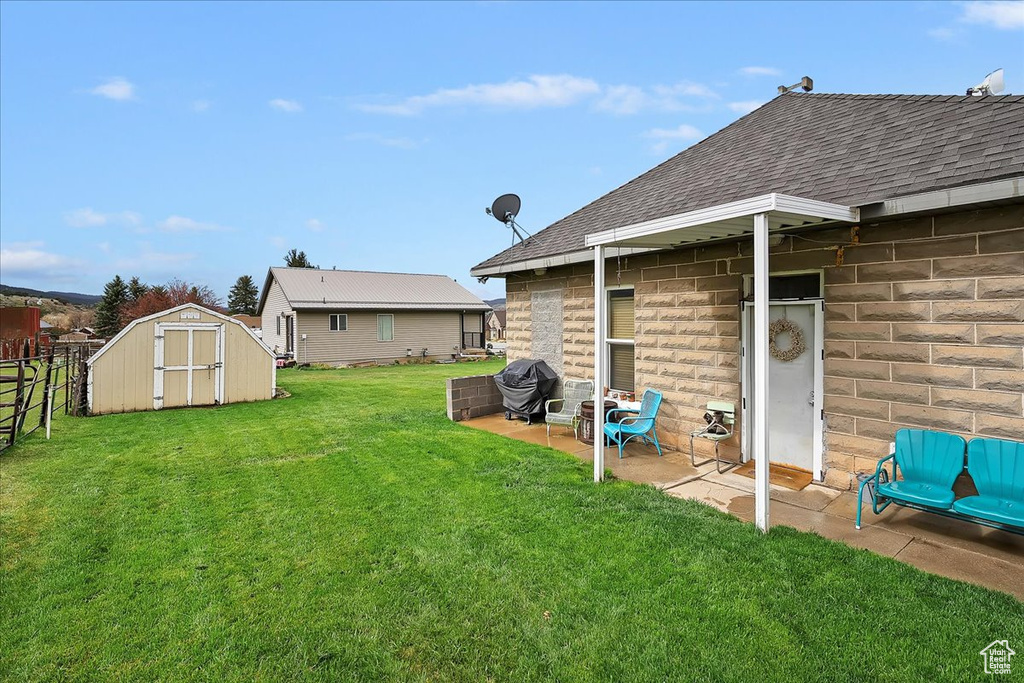 View of yard featuring a patio area, a shed, an outbuilding, and fence