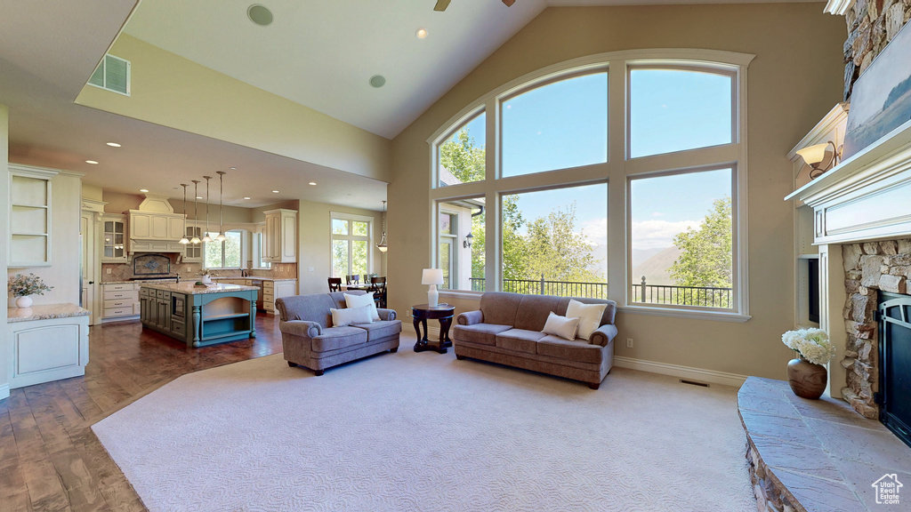 Living area with a fireplace, dark wood finished floors, recessed lighting, a towering ceiling, and visible vents