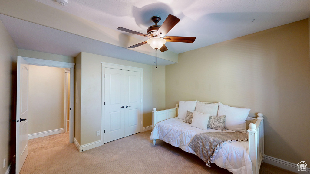 Bedroom featuring a ceiling fan, baseboards, light colored carpet, and a closet