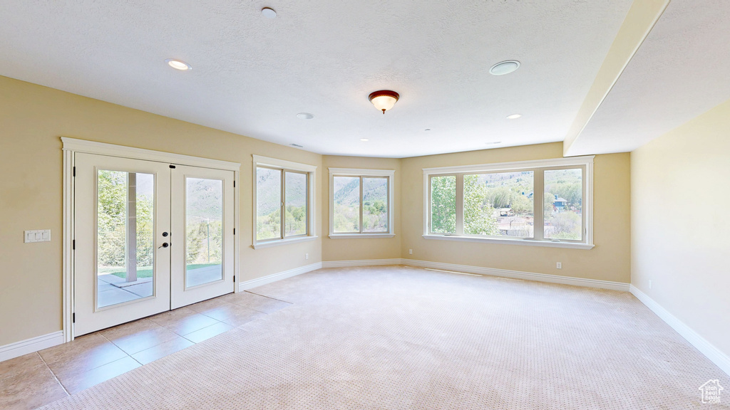 Spare room featuring french doors, recessed lighting, baseboards, and light carpet