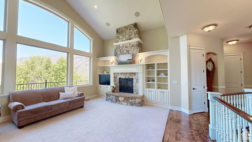 Living room with a high ceiling, plenty of natural light, baseboards, and a stone fireplace