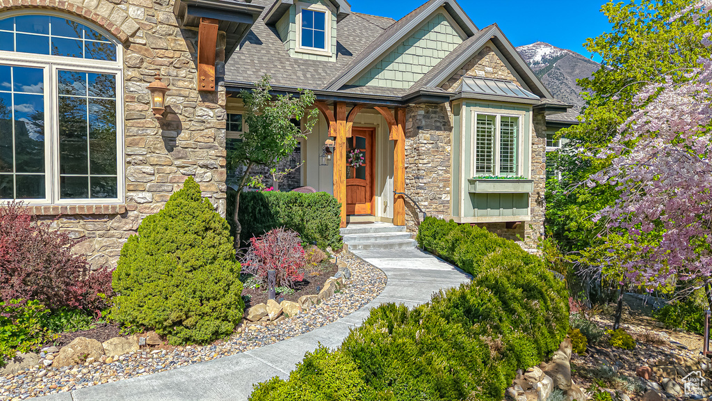 Property entrance featuring a shingled roof and stone siding