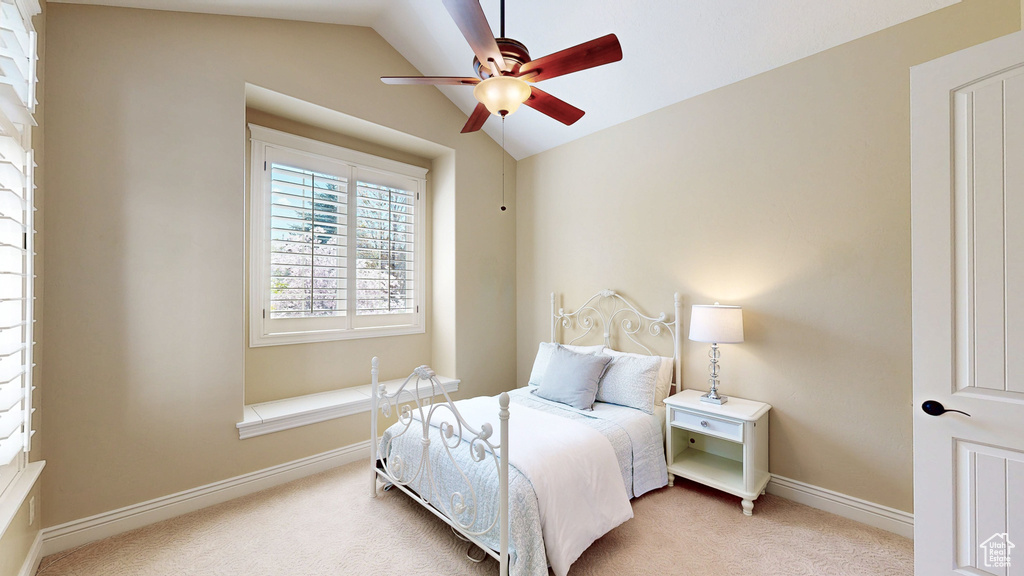 Carpeted bedroom featuring a ceiling fan, baseboards, and vaulted ceiling