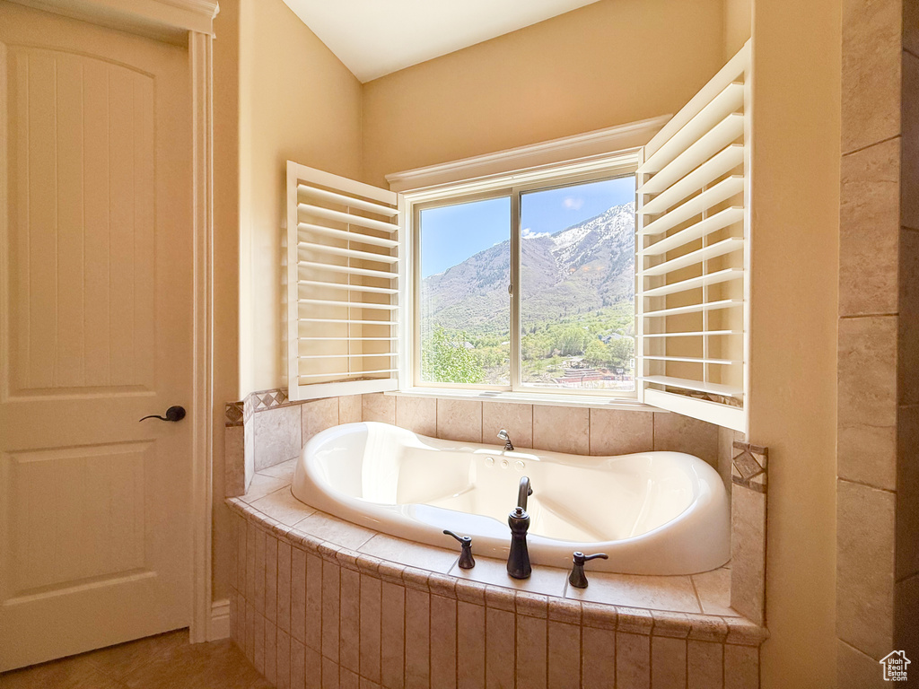 Full bath with tile patterned floors, a mountain view, and a garden tub
