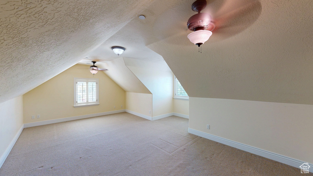 Additional living space featuring ceiling fan, carpet, and a wealth of natural light