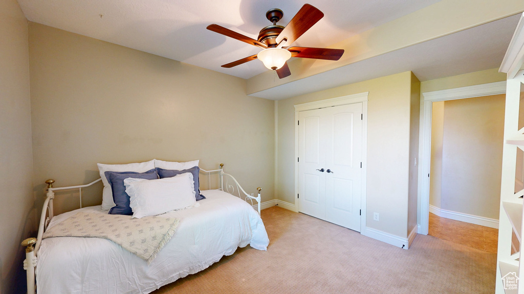 Bedroom with baseboards, ceiling fan, a closet, and light carpet