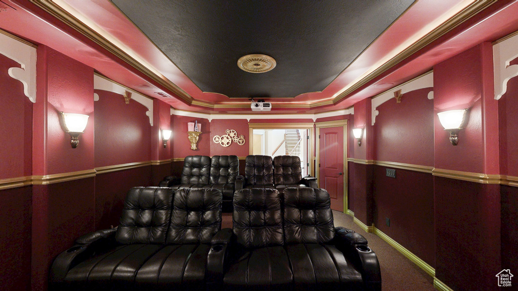 Carpeted cinema room featuring a raised ceiling and wainscoting