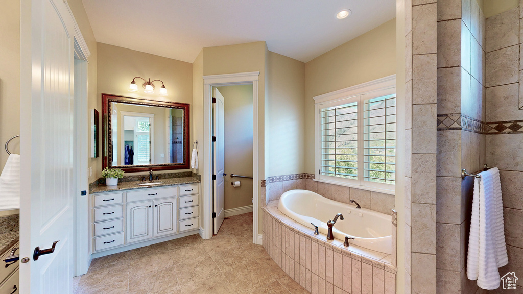 Bathroom featuring tile patterned floors, a bath, and vanity