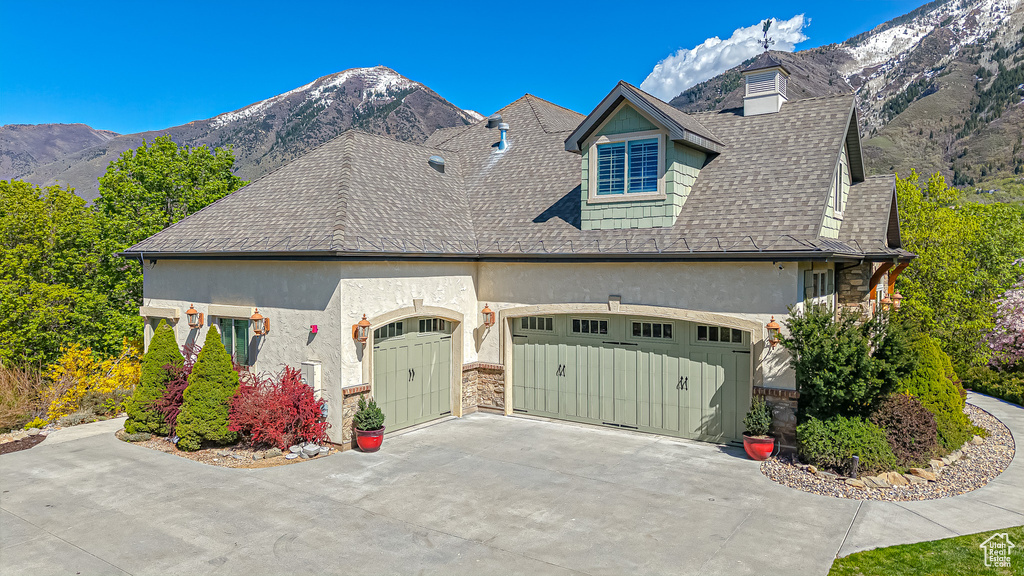 View of front of property featuring stone siding, stucco siding, an attached garage, a mountain view, and driveway