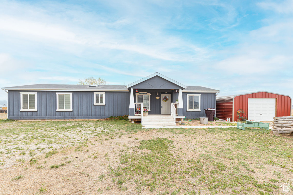 View of front of home with board and batten siding, an outbuilding, a front yard, and a detached garage