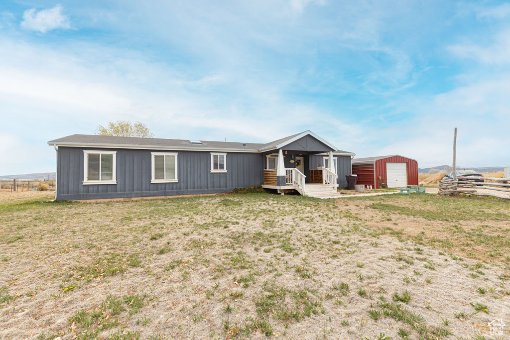 Rear view of house featuring a detached garage, an outbuilding, board and batten siding, and a yard