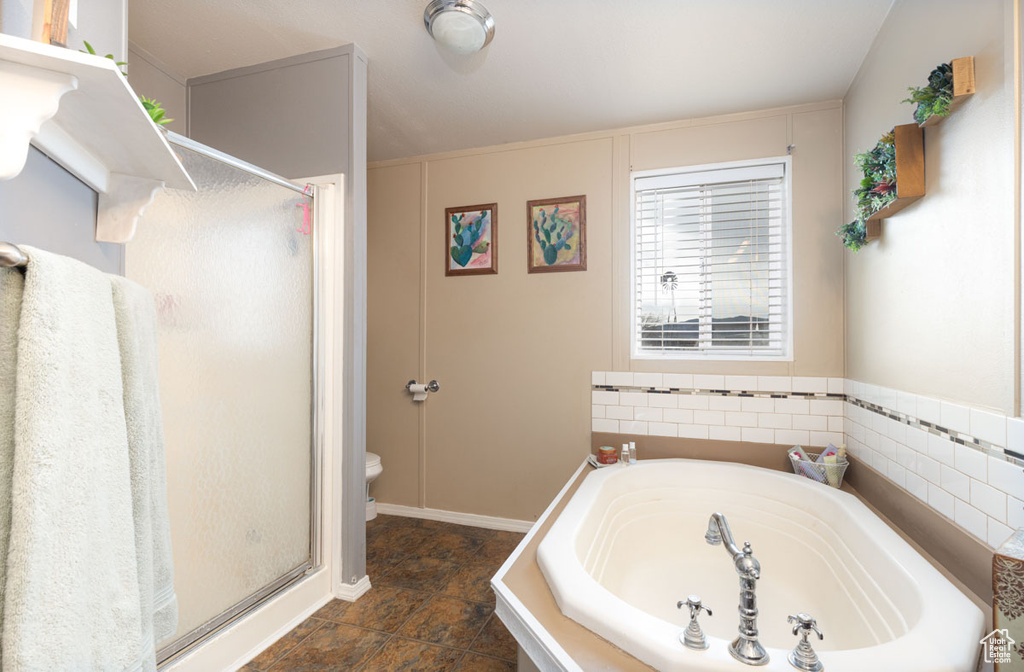 Bathroom featuring toilet, a garden tub, and a stall shower