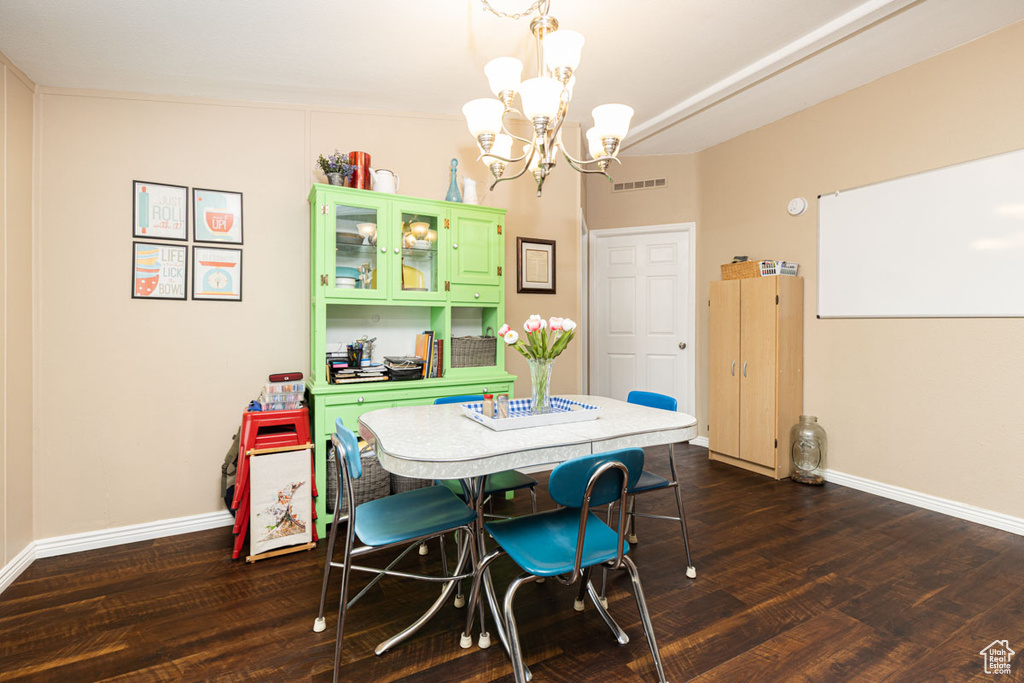 Dining area with baseboards, visible vents, dark wood-type flooring, and a notable chandelier