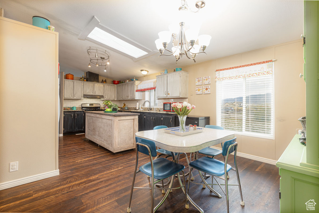 Dining area featuring baseboards, dark wood finished floors, lofted ceiling with skylight, and a notable chandelier