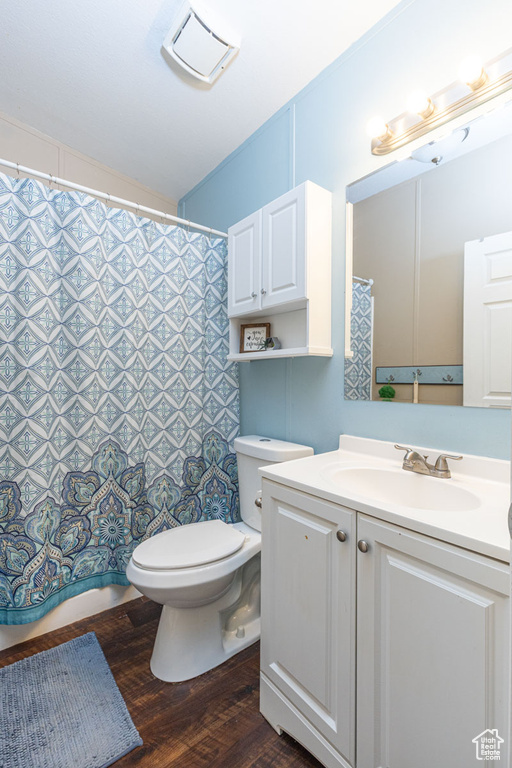 Bathroom with vanity, curtained shower, toilet, and wood finished floors