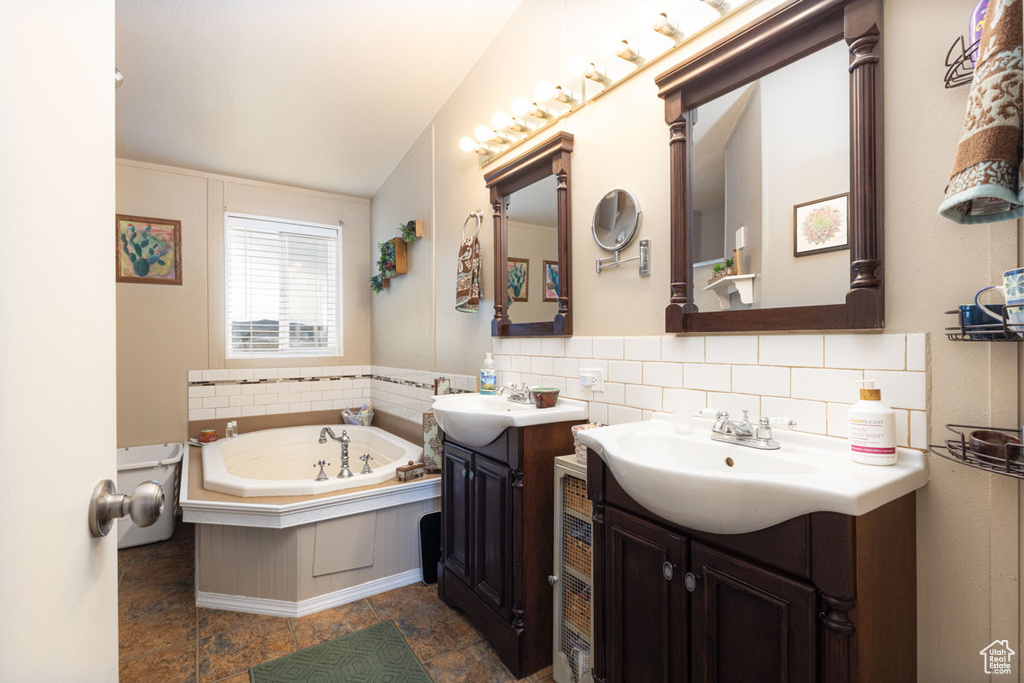 Full bath featuring two vanities, a sink, and a bath