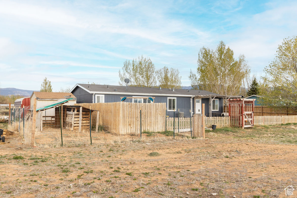 Rear view of house with exterior structure, fence, and an outbuilding