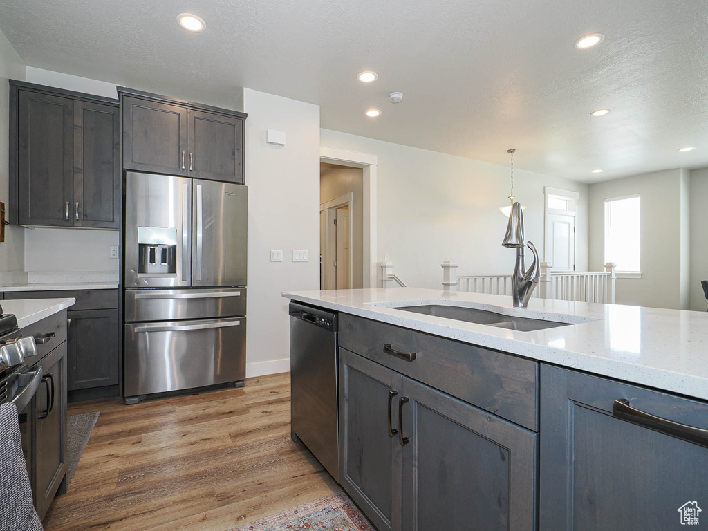 Kitchen with stainless steel appliances, recessed lighting, a sink, and light wood finished floors