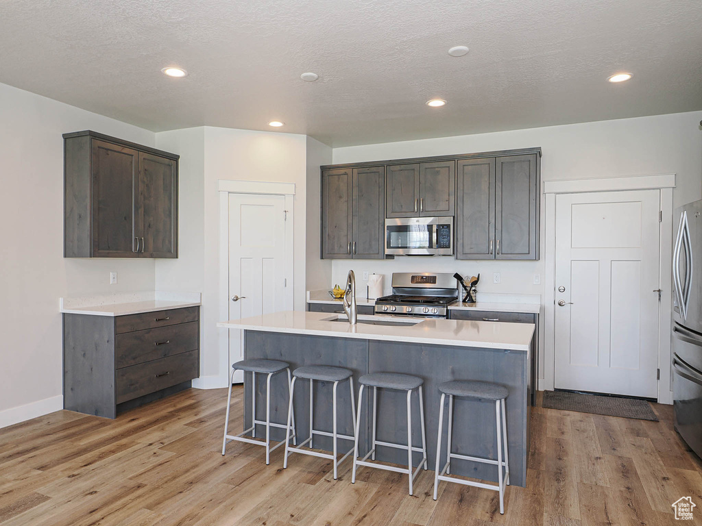 Kitchen with appliances with stainless steel finishes, a breakfast bar area, and light wood-style flooring