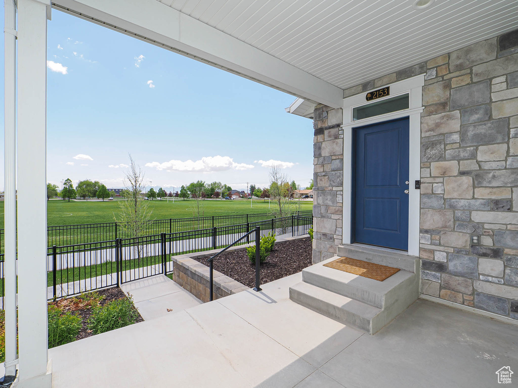 Entrance to property featuring fence, a lawn, and stone siding