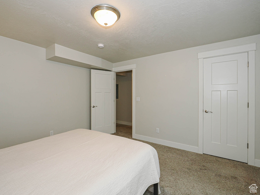 Carpeted bedroom with baseboards and a textured ceiling