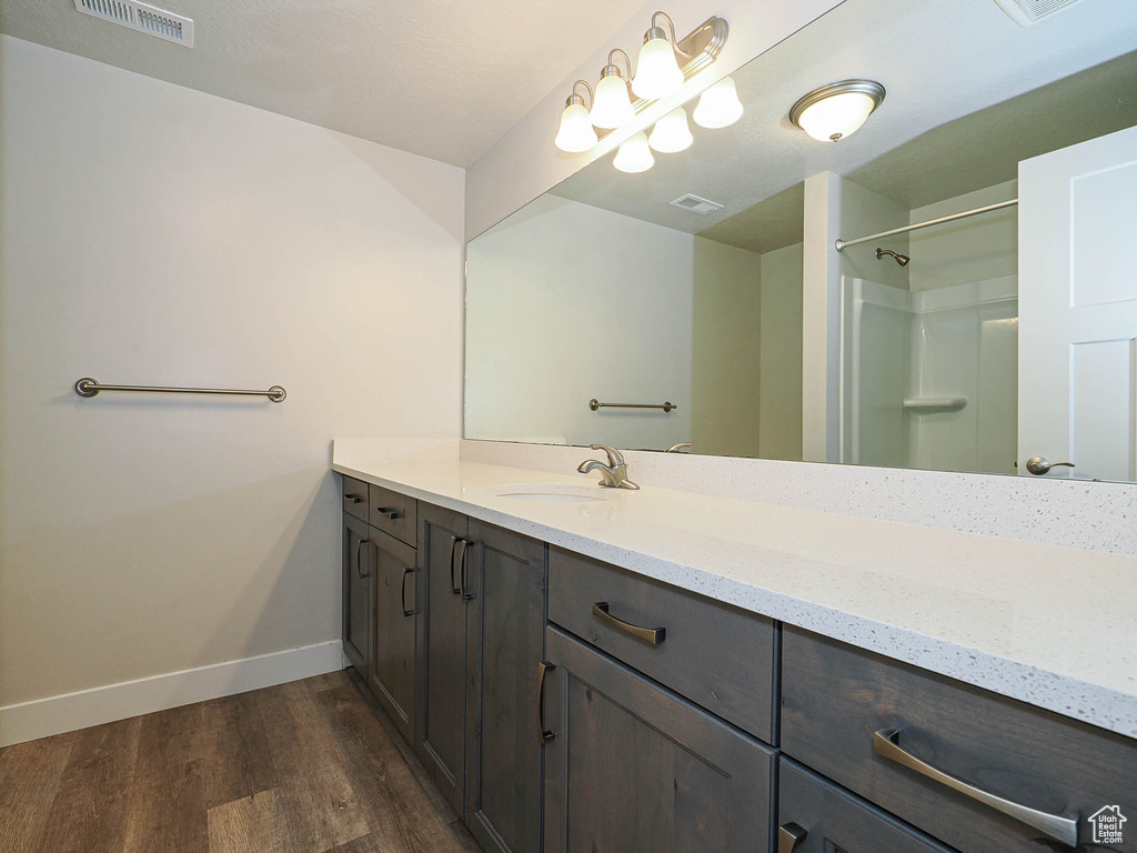 Bathroom with visible vents, baseboards, wood finished floors, and vanity