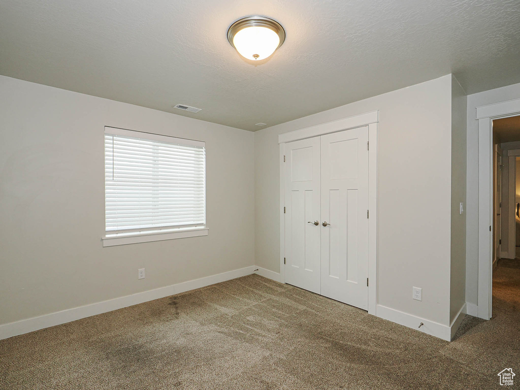Unfurnished bedroom featuring carpet floors, baseboards, a closet, and visible vents