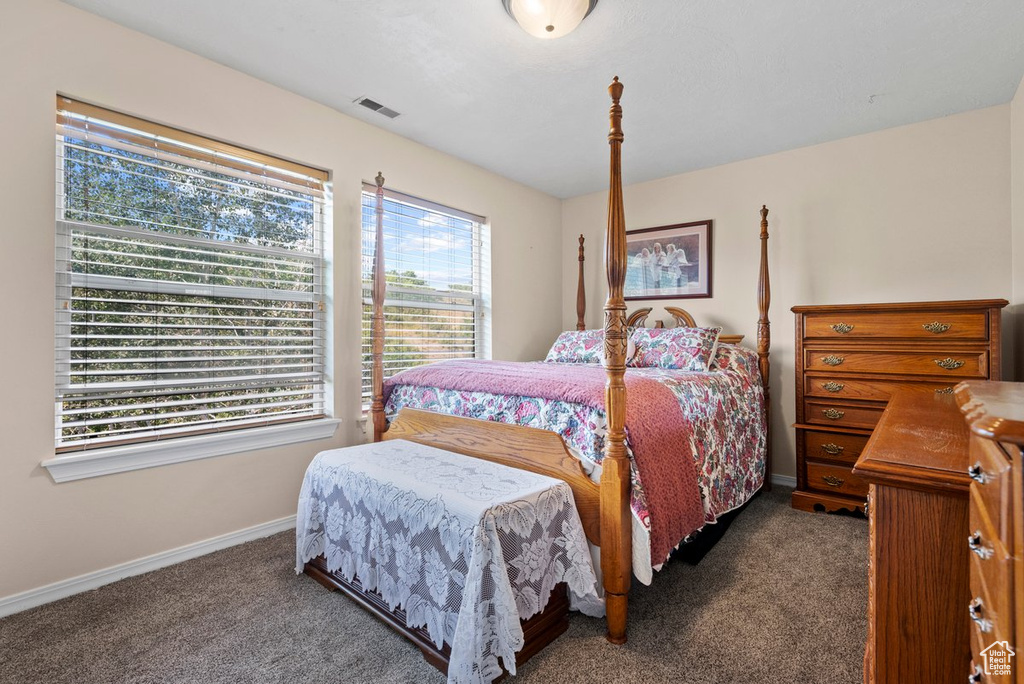 Bedroom featuring baseboards, dark colored carpet, and visible vents