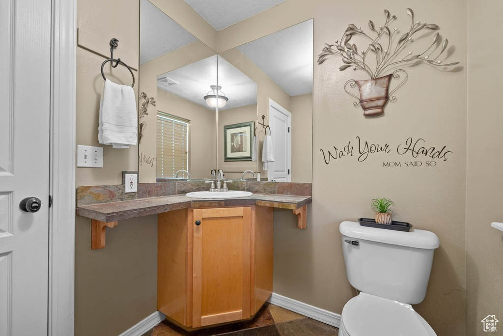 Bathroom with baseboards, toilet, and vanity