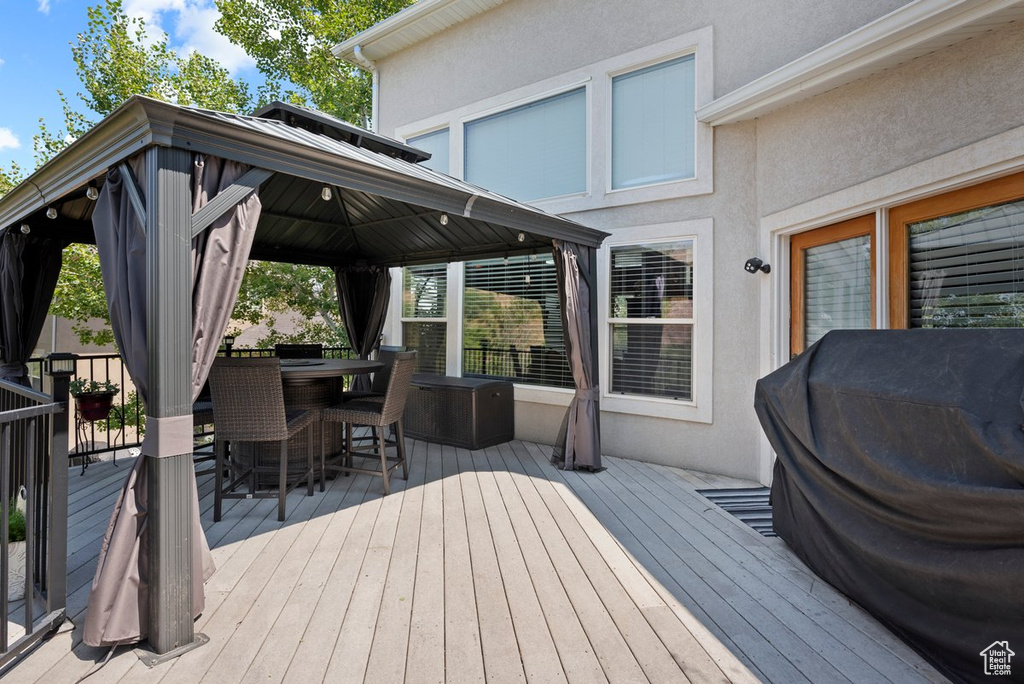 Deck with a gazebo, outdoor dry bar, and a grill