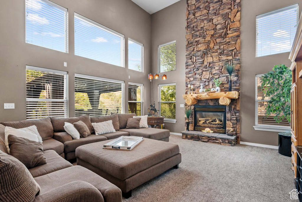 Carpeted living room with a fireplace, plenty of natural light, and a towering ceiling