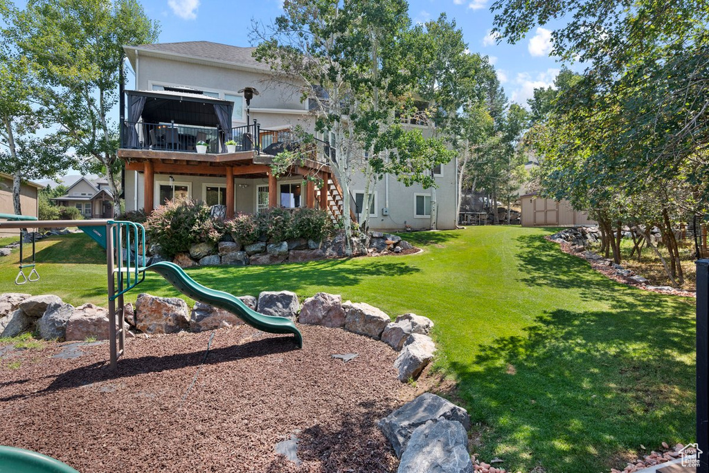 Rear view of property with a lawn, a playground, and stucco siding